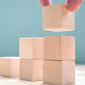 Image of building blocks being stacked together in an upward motion