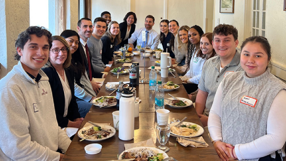 A group of smiling adults and SCU students seated at a dinner table.