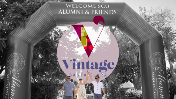 Two men and a woman holding hands underneath an inflatable arch reading