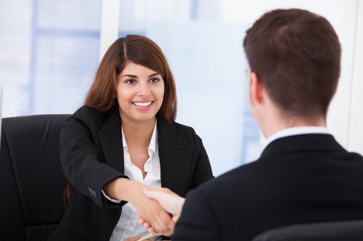 Two people in business attire shaking hands during an interview. 