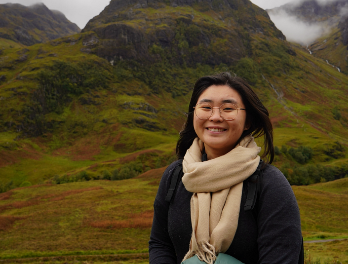 Decorative; student smiling in front of a mountain landscape