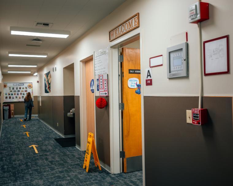 A hallway with a Welcome sign and a Front Desk sign next to an open door.