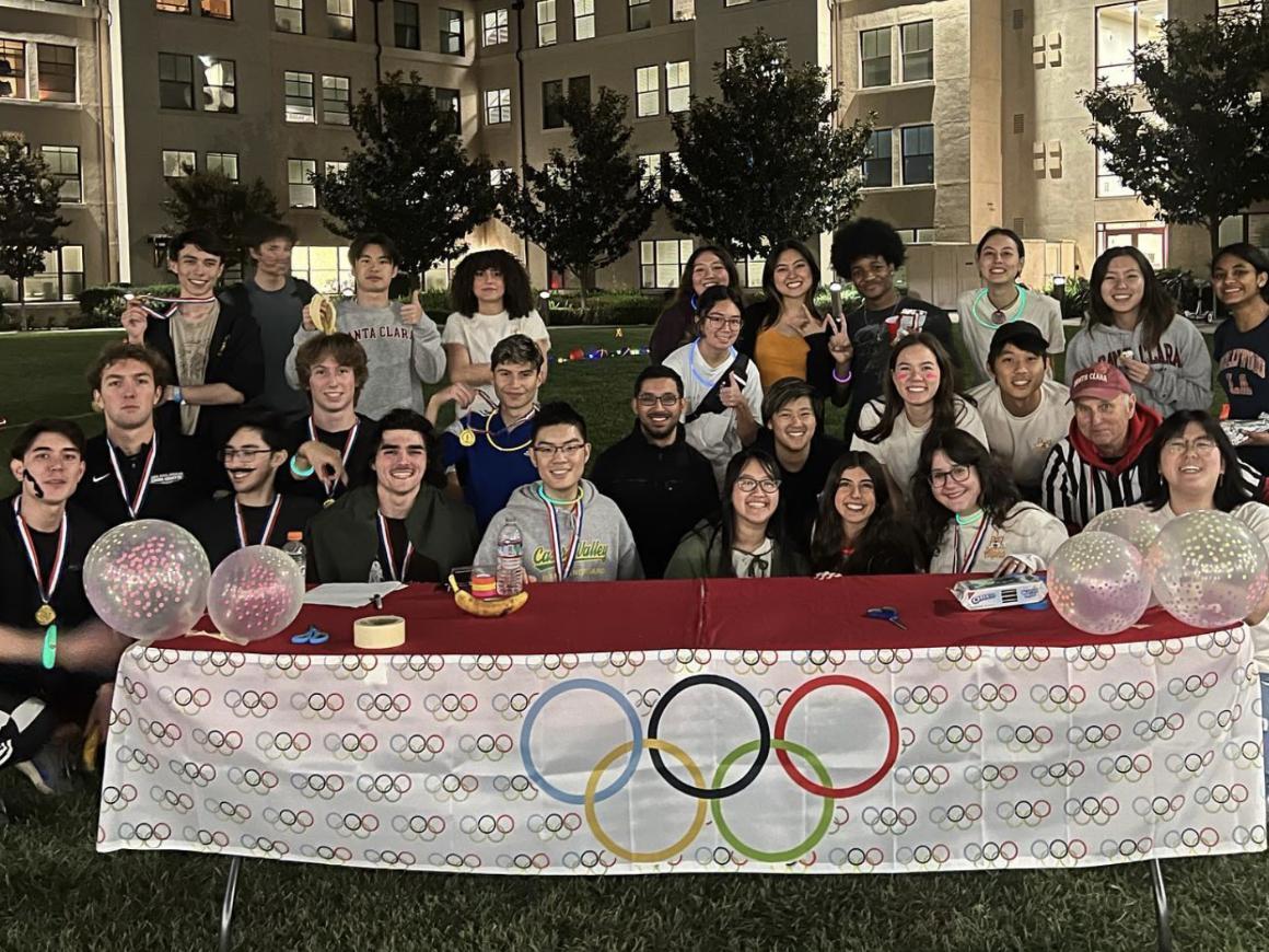 A bunch of people behind a table with an Olympics logo