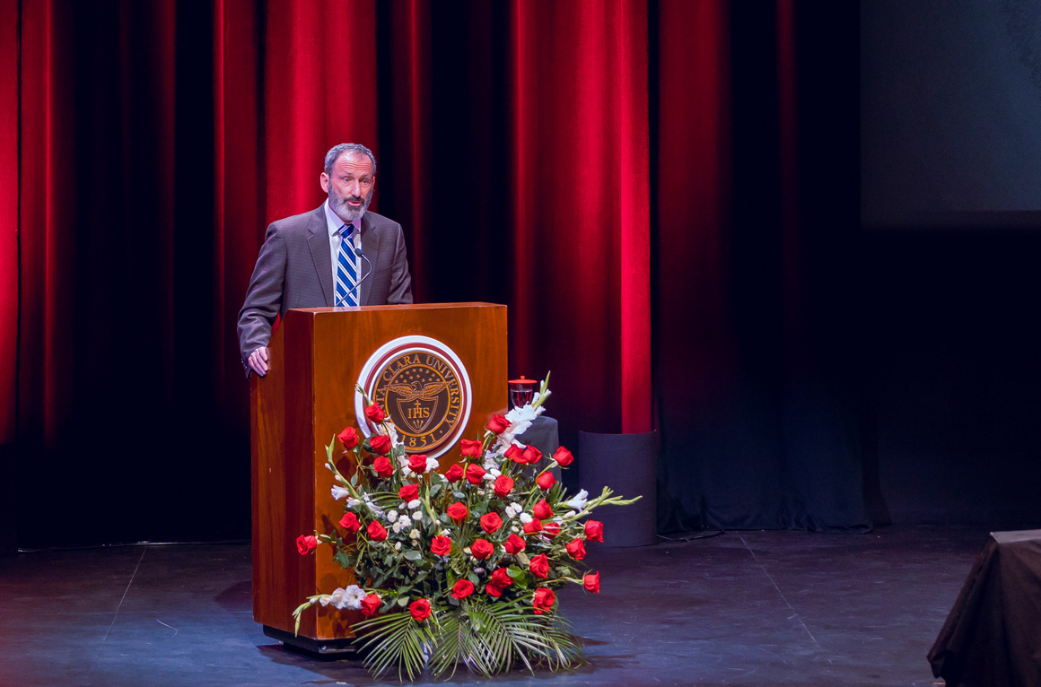 Provost and EVP Glaser speaking at a podium with a Santa Clara University seal