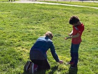 Adult and child on a nature hunt in grass for Garden Play Project image link to story