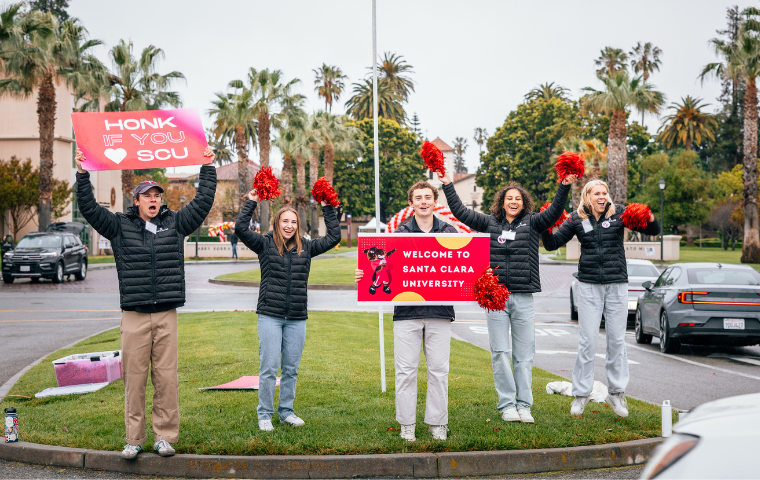 A group of students cheering and welcoming new students to campus