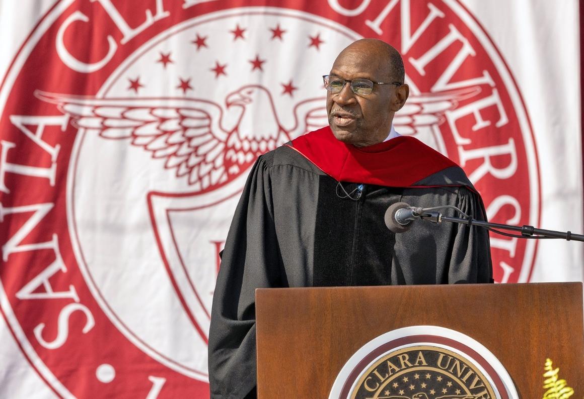 a black man wearing academic robes at a podium