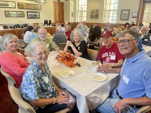 Elderly alumni sit around a table for a thanksgiving themed meal