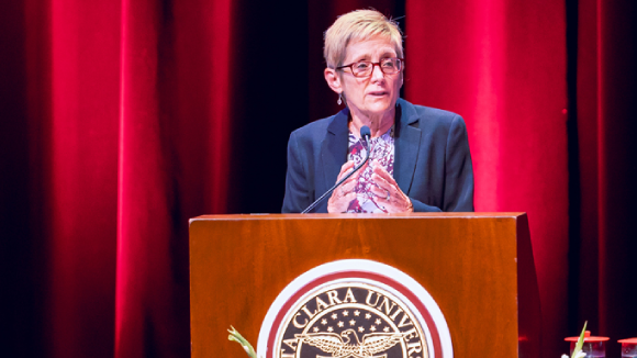 Santa Clara University President Julie Sullivan speaking from a podium.