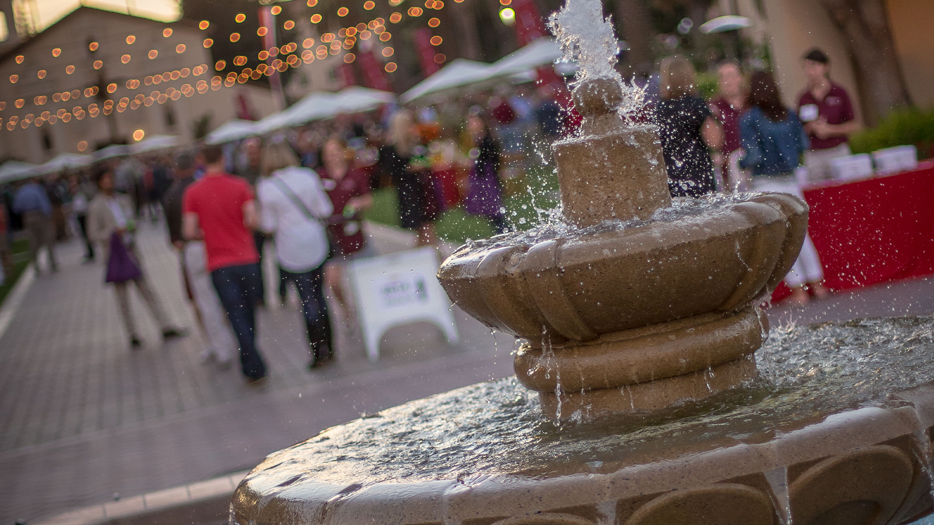 A fountain in front of a large crowd of people on Abby Sobrato Mall 