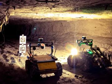 Two autonomous robots illuminate a target found in a mining tunnel