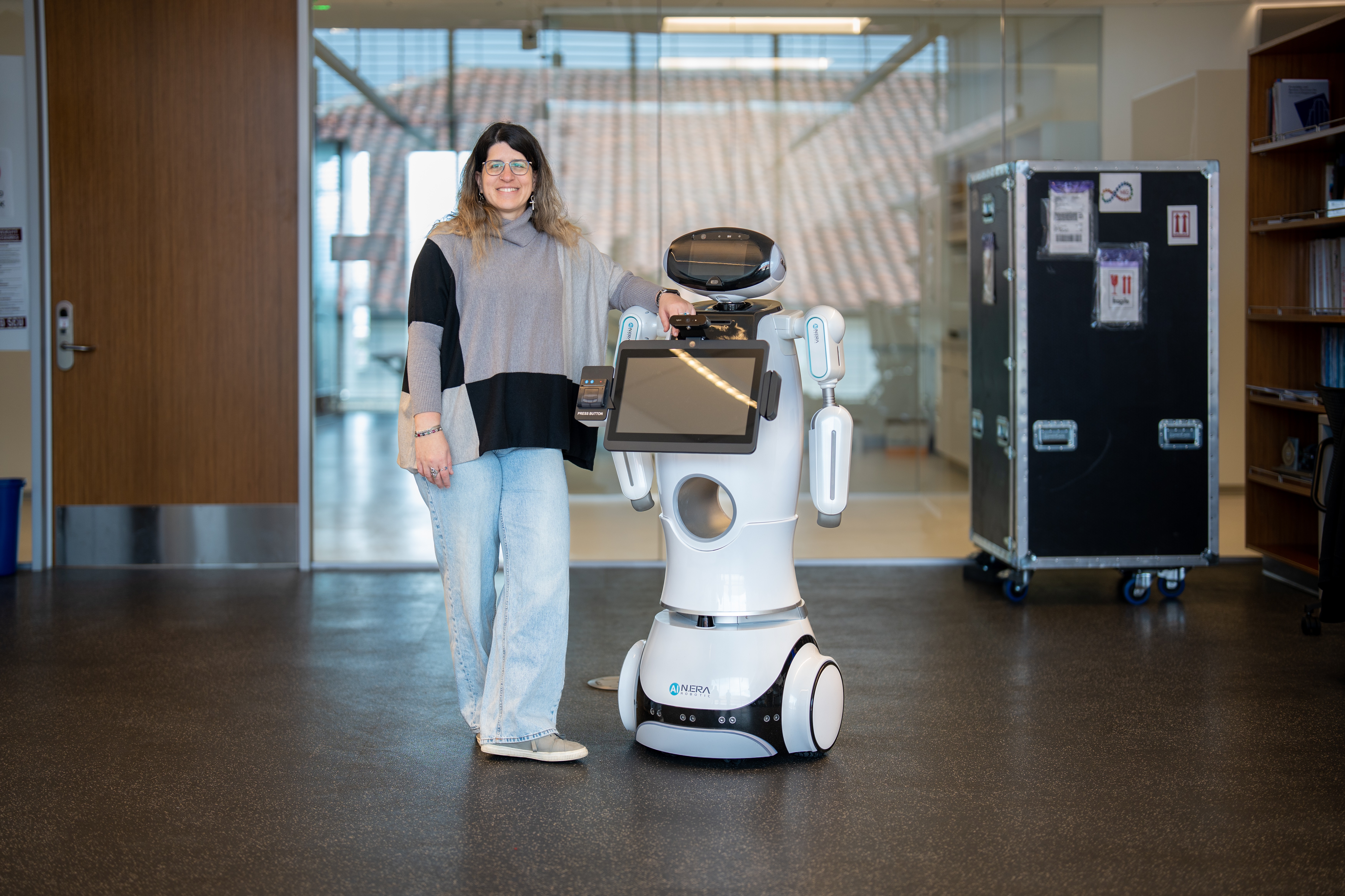 A photo of Maria Kyrarini posing with a robot in front of a lab