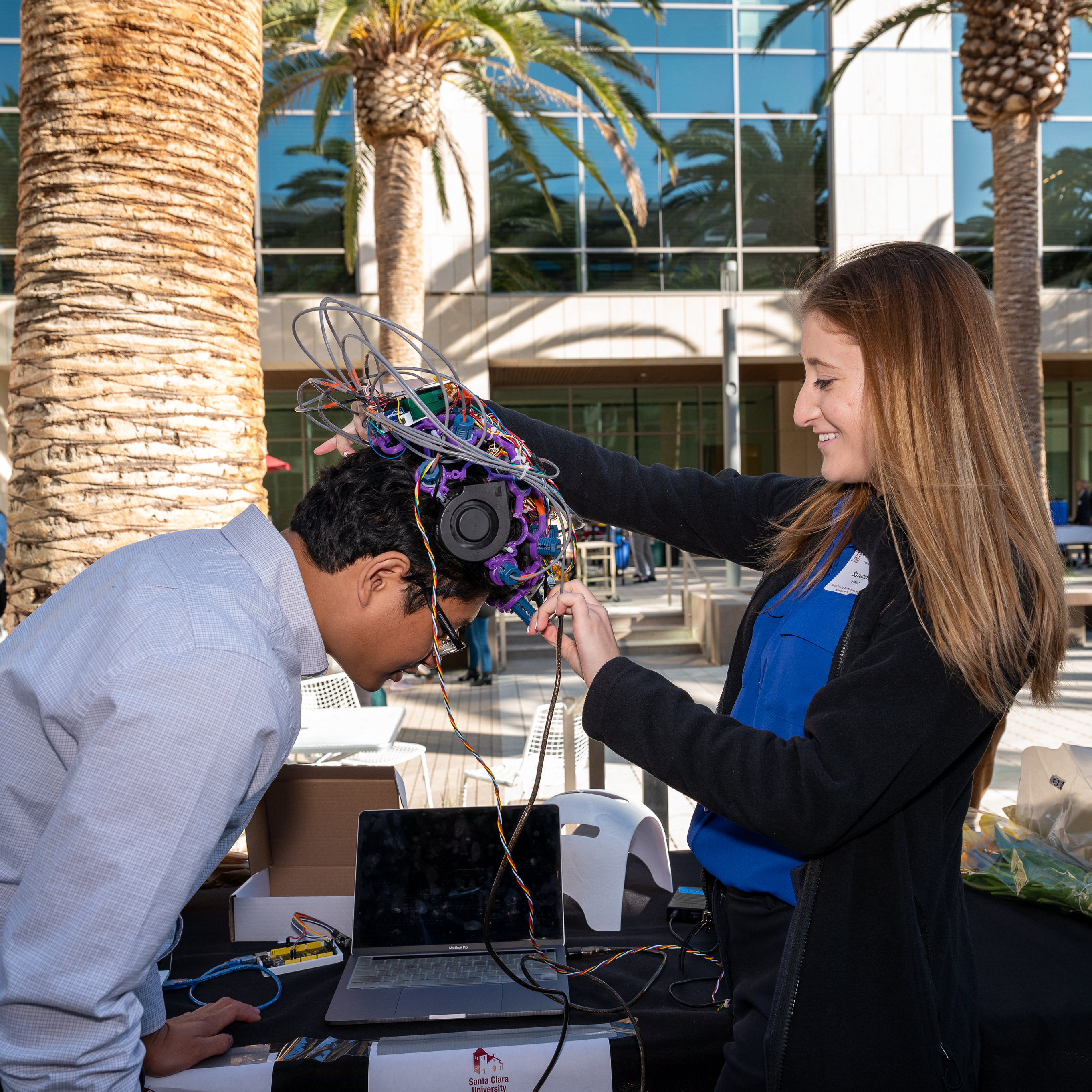 Student Samantha Perez demonstrates the NeuroGen EEG and Near-Infrared Light Stimulation helmet on a Senior Design guest image link to story