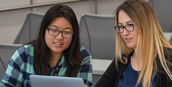 Two students looking at a laptop 