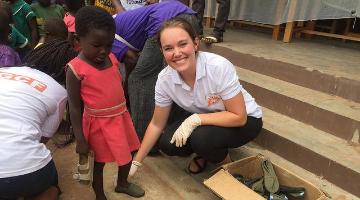 Students working in a global fellows program in Ghana. A small girl is also seen in the image. 